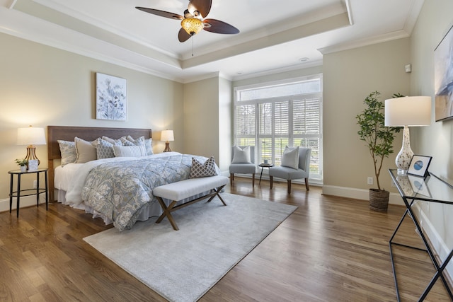 bedroom featuring a tray ceiling, wood finished floors, and crown molding