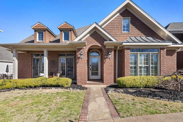 view of front of house featuring a standing seam roof, a front lawn, brick siding, and metal roof