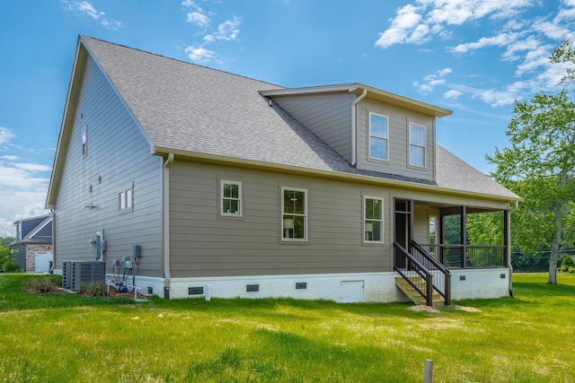 rear view of house with central AC unit and a lawn