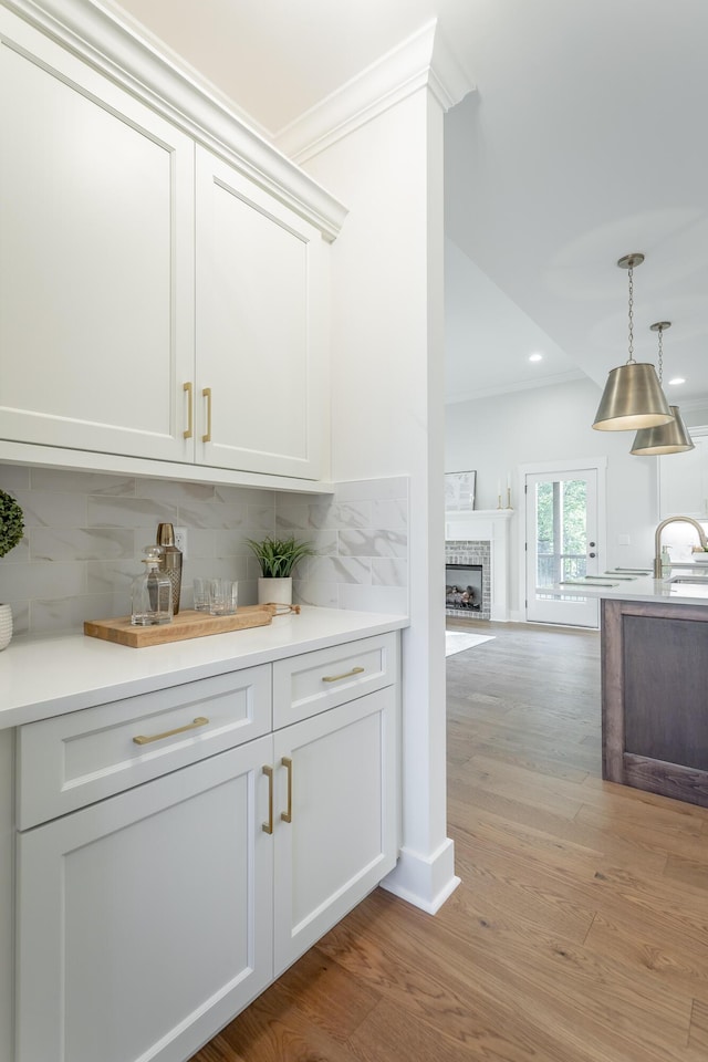 bar featuring white cabinetry, backsplash, and light wood-type flooring