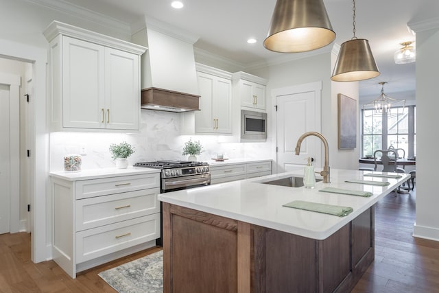 kitchen with sink, decorative light fixtures, custom range hood, and white cabinets