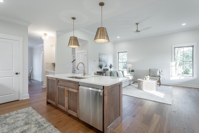 kitchen with pendant lighting, sink, crown molding, dishwasher, and a kitchen island with sink