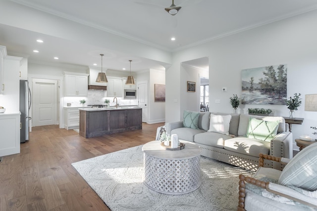 living room with ornamental molding, sink, and hardwood / wood-style floors