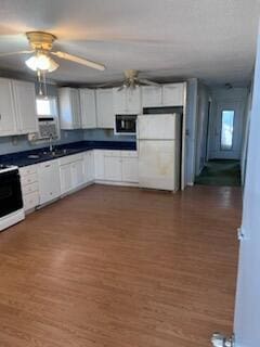 kitchen with dark wood-type flooring, range, black microwave, white cabinets, and white fridge