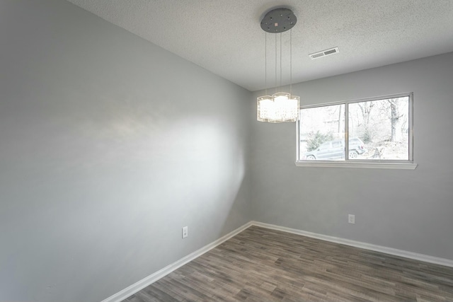 unfurnished room with dark hardwood / wood-style floors, a notable chandelier, and a textured ceiling