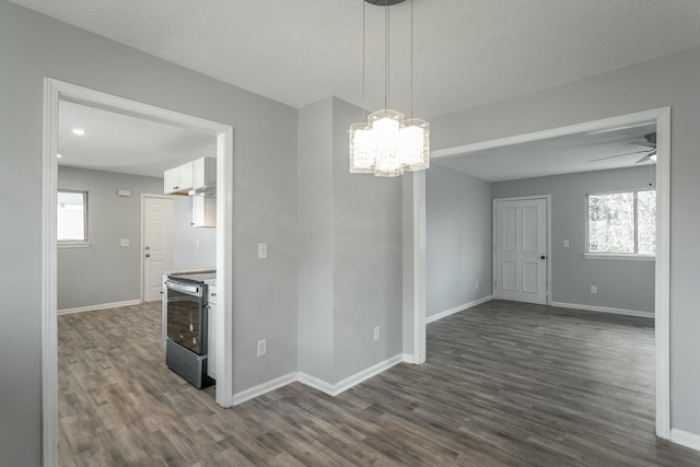 interior space featuring dark wood-type flooring, a textured ceiling, electric range, pendant lighting, and white cabinets