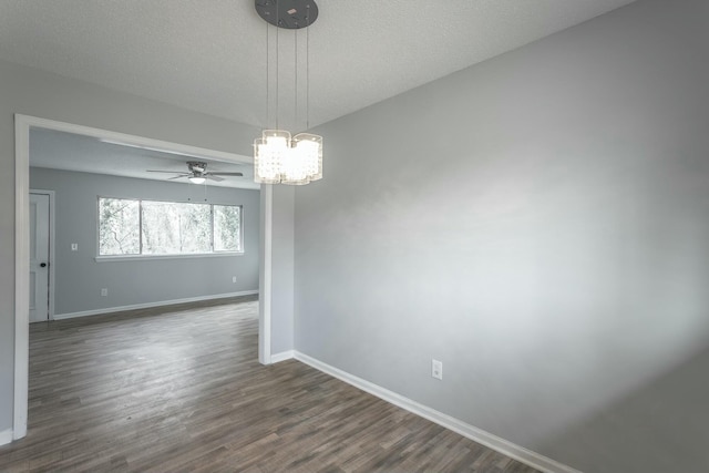 empty room featuring dark hardwood / wood-style floors, ceiling fan with notable chandelier, and a textured ceiling