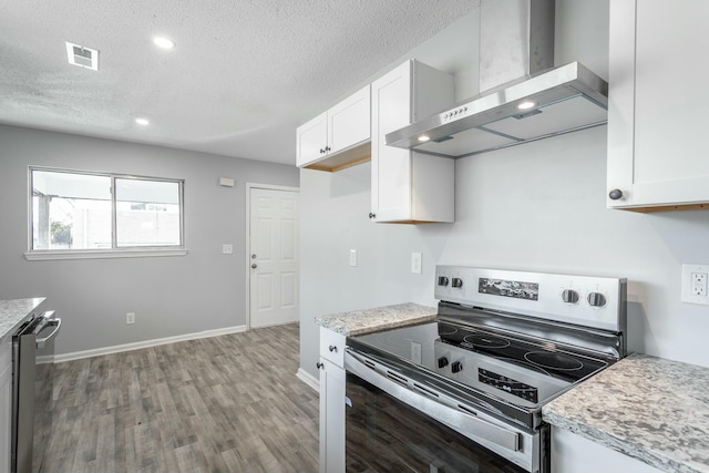 kitchen featuring white cabinetry, a textured ceiling, appliances with stainless steel finishes, light hardwood / wood-style floors, and wall chimney range hood