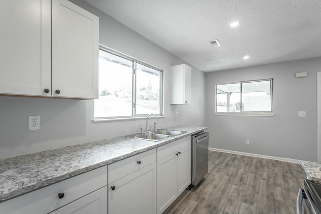 kitchen with sink, appliances with stainless steel finishes, white cabinetry, light hardwood / wood-style floors, and a textured ceiling