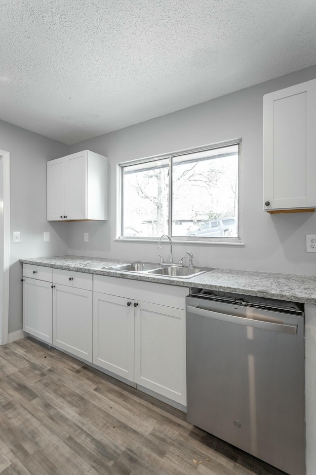 kitchen featuring white cabinetry, sink, stainless steel dishwasher, and light wood-type flooring