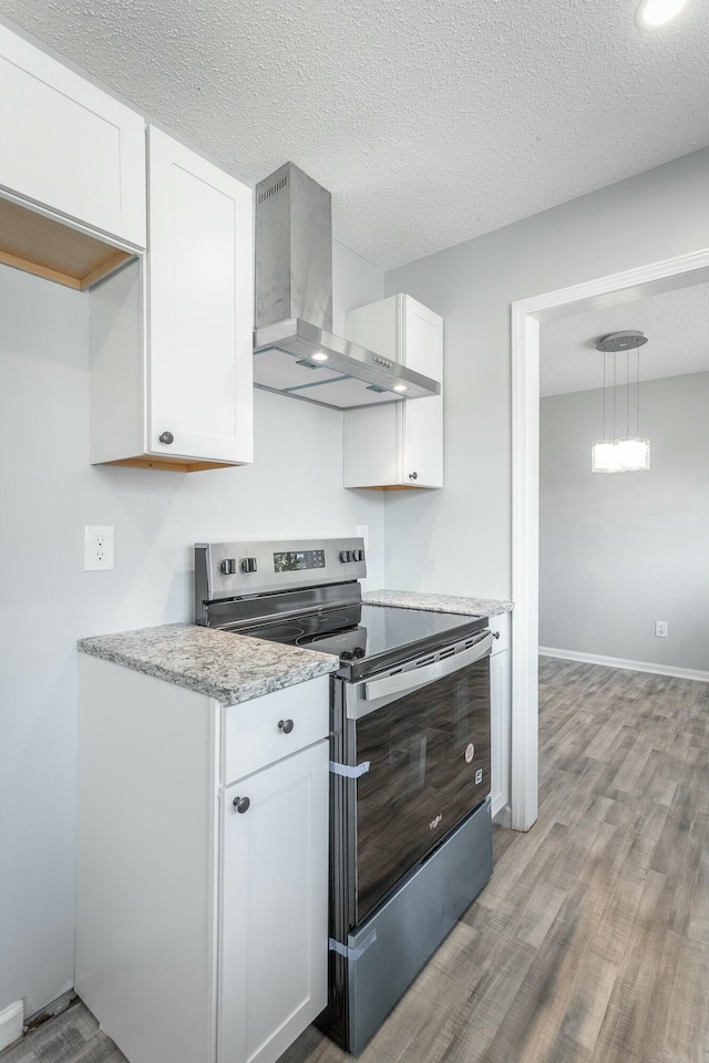 kitchen with white cabinetry, hanging light fixtures, ventilation hood, stainless steel electric range oven, and light wood-type flooring