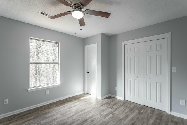 unfurnished bedroom with multiple windows, hardwood / wood-style flooring, and a textured ceiling