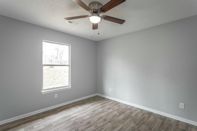 spare room with ceiling fan, a textured ceiling, and light wood-type flooring