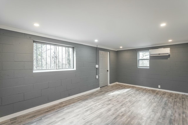 basement featuring light hardwood / wood-style floors and an AC wall unit