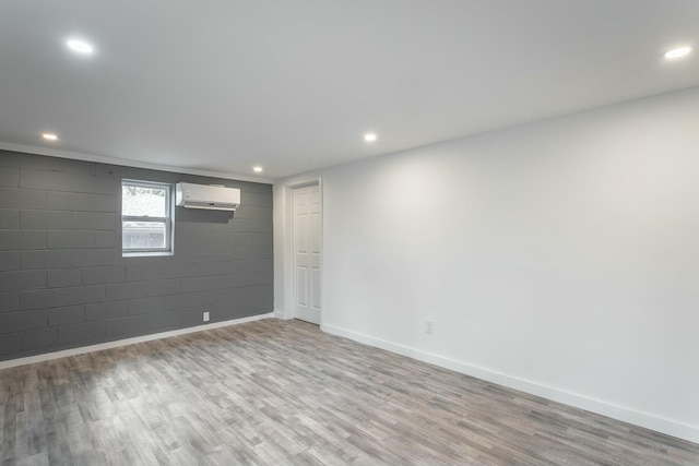 basement with a wall mounted air conditioner and light hardwood / wood-style flooring