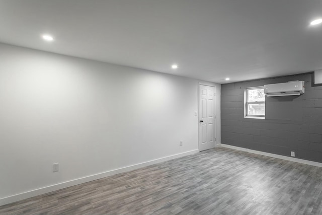 basement with a wall unit AC and light hardwood / wood-style floors