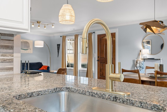 kitchen with sink, track lighting, ornamental molding, stone counters, and white cabinets