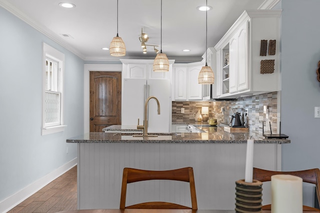 kitchen with stone countertops, white cabinets, hanging light fixtures, white refrigerator, and kitchen peninsula