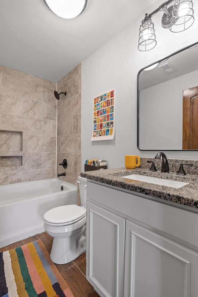 full bathroom featuring tiled shower / bath, vanity, and toilet