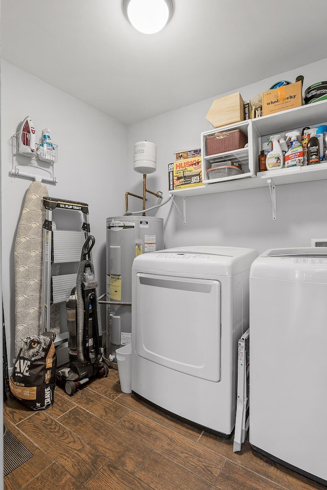 laundry room featuring water heater, washing machine and clothes dryer, and dark hardwood / wood-style flooring