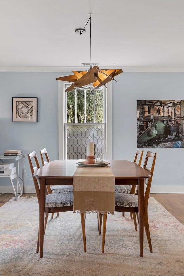 dining space featuring ornamental molding and light hardwood / wood-style floors