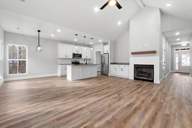 unfurnished living room featuring light hardwood / wood-style flooring, beam ceiling, a wealth of natural light, and high vaulted ceiling