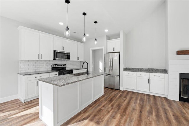 kitchen with sink, white cabinetry, decorative light fixtures, stainless steel appliances, and a kitchen island with sink