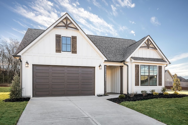 modern inspired farmhouse featuring roof with shingles, concrete driveway, board and batten siding, a garage, and a front lawn