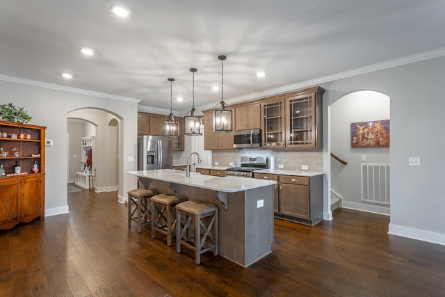 kitchen featuring a kitchen bar, hanging light fixtures, a center island with sink, dark hardwood / wood-style flooring, and stainless steel appliances