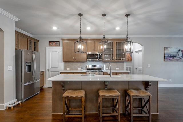 kitchen featuring sink, appliances with stainless steel finishes, dark hardwood / wood-style flooring, pendant lighting, and a kitchen island with sink