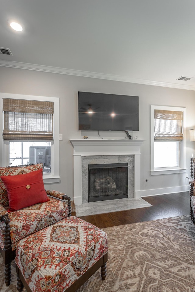 living room featuring a high end fireplace, ornamental molding, and wood-type flooring