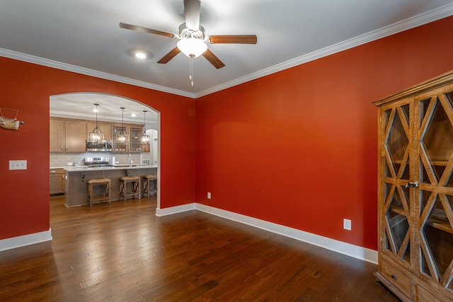 unfurnished living room featuring dark wood-type flooring, ornamental molding, and ceiling fan