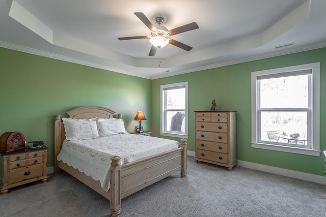 carpeted bedroom with a tray ceiling and ceiling fan