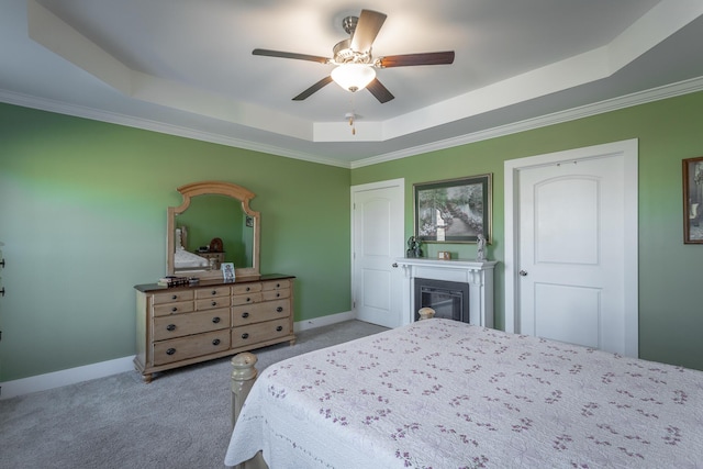 bedroom with light carpet, a tray ceiling, crown molding, and ceiling fan