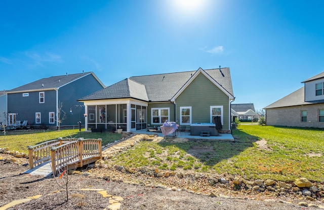 back of house featuring a lawn, a sunroom, a patio, and a hot tub