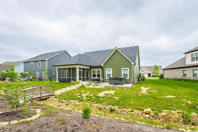 rear view of property featuring a sunroom, a shingled roof, a patio area, a hot tub, and a yard