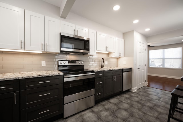 kitchen featuring stainless steel appliances, sink, white cabinets, and decorative backsplash