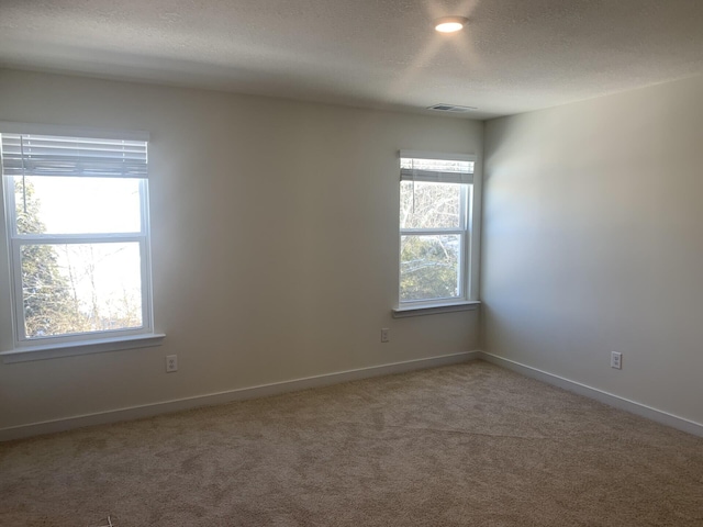 carpeted empty room featuring a textured ceiling