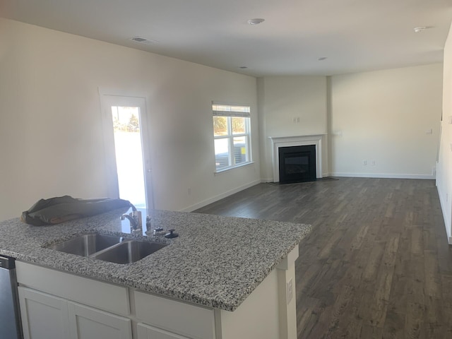 kitchen with light stone countertops, sink, white cabinets, and dark hardwood / wood-style floors