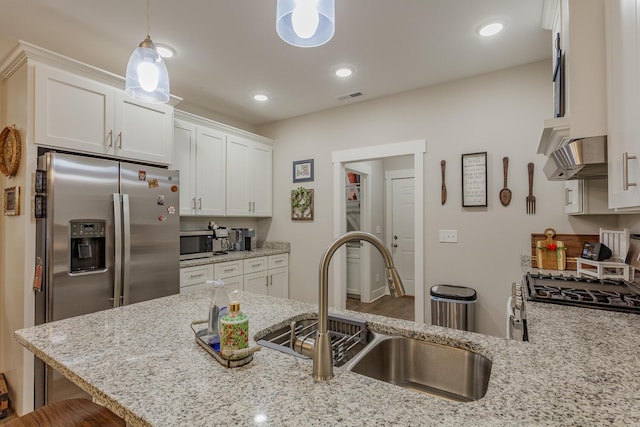 kitchen with sink, white cabinetry, hanging light fixtures, stainless steel appliances, and a kitchen bar