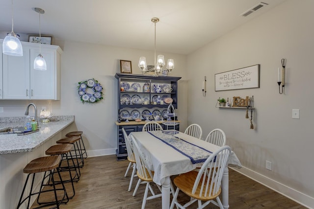 dining area with dark hardwood / wood-style flooring, sink, and a notable chandelier