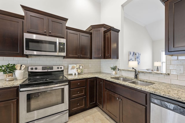 kitchen with appliances with stainless steel finishes, sink, backsplash, light tile patterned floors, and light stone countertops