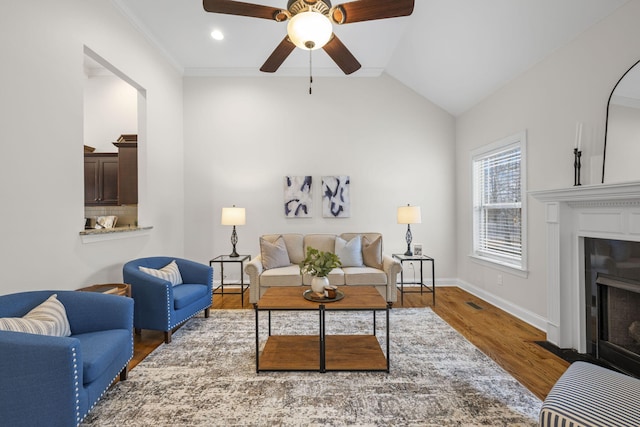 living room featuring ceiling fan, wood-type flooring, vaulted ceiling, and ornamental molding