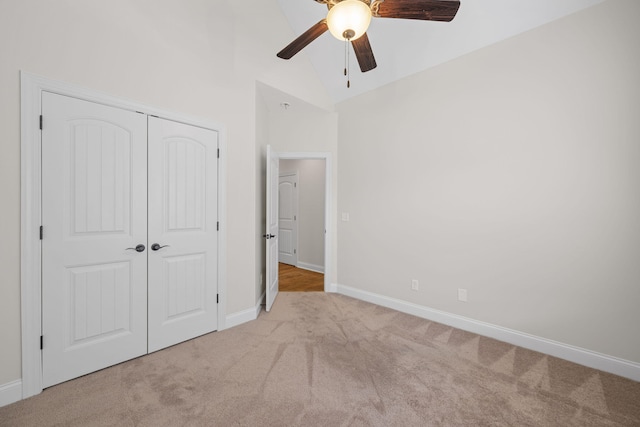 unfurnished bedroom featuring light carpet, high vaulted ceiling, a closet, and ceiling fan