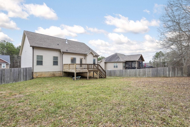 rear view of house with a wooden deck and a lawn