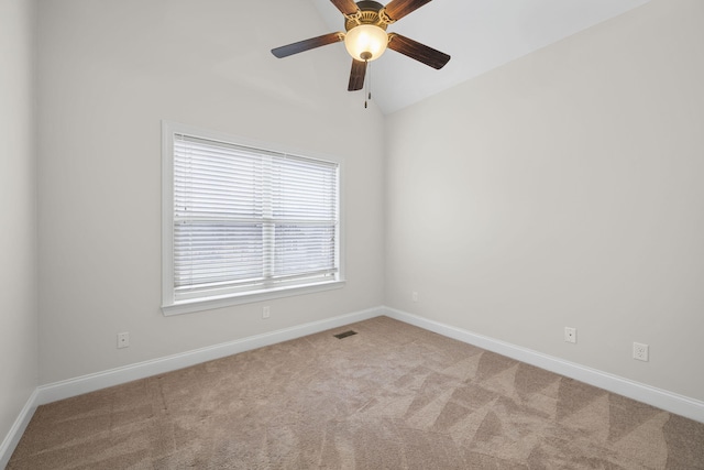 carpeted spare room featuring vaulted ceiling and ceiling fan