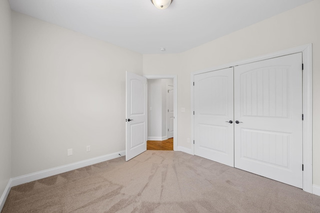 unfurnished bedroom featuring light colored carpet and a closet