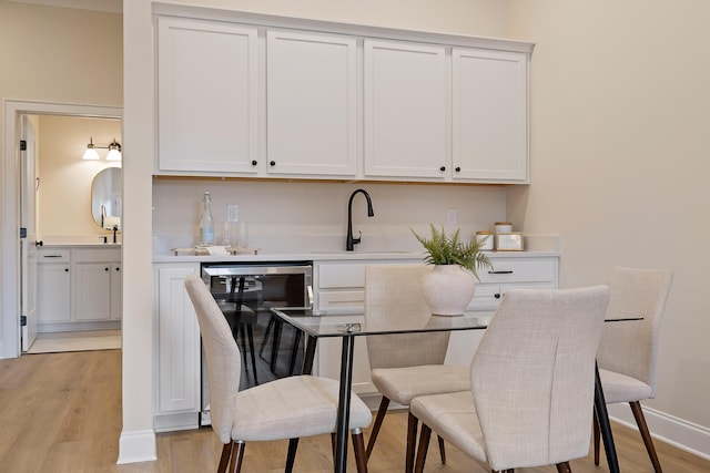 interior space with sink, light hardwood / wood-style floors, and white cabinets