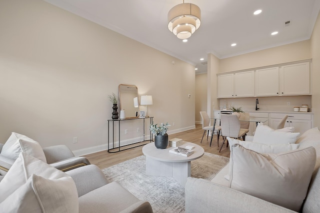 living room featuring ornamental molding, sink, and light hardwood / wood-style floors