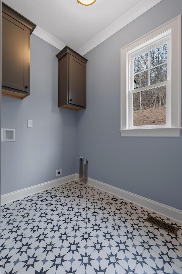 clothes washing area with electric dryer hookup, ornamental molding, and cabinets